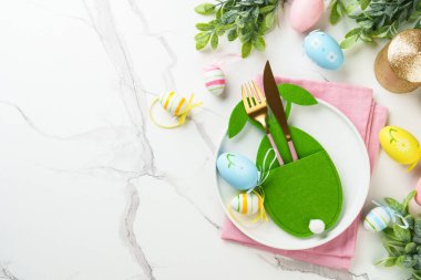 Beyaz arka planda süslemeleri olan Paskalya yemekleri. Beyaz tabak, çatal bıçak takımı ve komik paskalya süslemeleri..