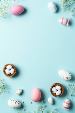 Paskalya yumurtaları. Paskalya bayramı kompozisyonu, güzel süslemeler ve çiçekler. Mavi arkaplanda üst görünüm.
