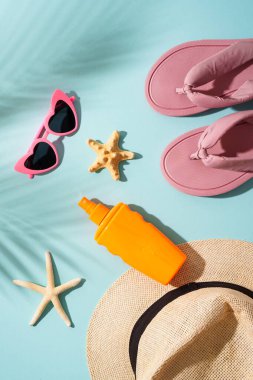 Plaj örtüsü ve mavi arka planda deniz kabukları olan aksesuarlar. Sert gölgeli üst görünüm.