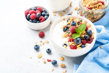 Taze böğürtlenli yoğurt ve beyaz masada granola..