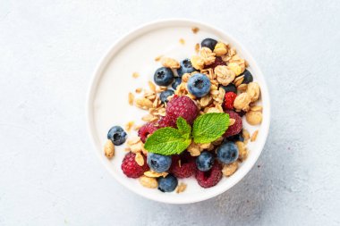 Beyaz masada taze böğürtlenli yoğurt ve tahıl gevreği. Sağlıklı atıştırmalıklar ya da kahvaltı. Üst görünüm.