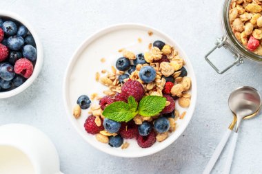 Beyaz masada taze böğürtlenli yoğurt ve tahıl gevreği. Sağlıklı atıştırmalıklar ya da kahvaltı. Diyet yemek..