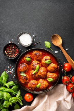 Domates soslu jöleli köfteler siyah zemin üzerinde demir tabakta. Metin için boşluk olan üst görünüm.