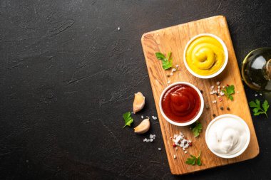 Kesme tahtasında ketçap, mayonez ve hardal var. Üst görünüm, tasarım için alan.