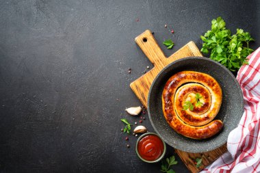 Sosis, ızgara et, domates soslu domuz sucuğu. Koyu mutfak masasında fotokopi alanı olan üst manzara.