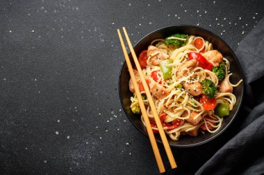 Kızarmış tavuğu sebzeyle karıştır ve siyah arka planda erişte. Asya mutfağı. Tasarım için alanı olan üst görünüm.