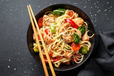 Erişteli tavuk kızartması ve siyah arka planda sebze. Düz görünüm.