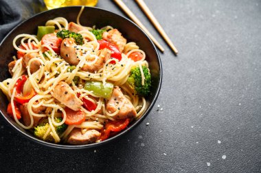 Kızarmış tavuğu sebzeyle karıştır ve siyah arka planda erişte. Asya mutfağı. Kapat..