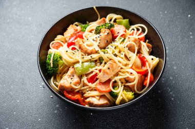 Kızarmış tavuğu sebzeyle karıştır ve siyah arka planda erişte. Asya mutfağı. Kapat..