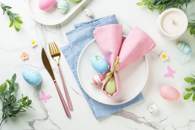Beyaz arka planda Paskalya sofrası. Beyaz tabak, çatal bıçak takımı ve paskalya süslemeleri. Düz yatıyordu.