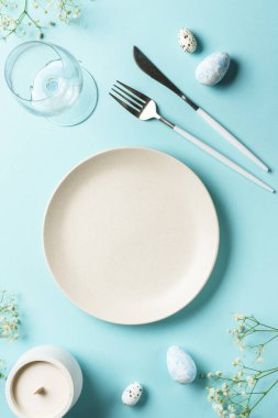 Yumurta ve çiçekli Paskalya masası. Mavi arkaplanda üst görünüm.