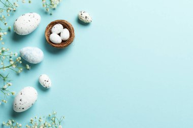 Yumurta ve çiçekli Paskalya arkaplanı. Mavi arka planda düz uzandı.