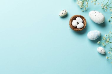 Yumurta ve çiçekli Paskalya arkaplanı. Mavi arka planda düz uzandı.