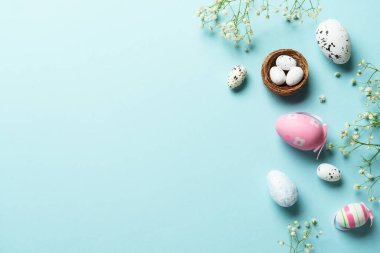 Paskalya yumurtaları. Paskalya bayramı kompozisyonu, güzel süslemeler ve çiçekler. Mavi arkaplanda üst görünüm.