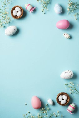 Paskalya yumurtaları. Paskalya bayramı kompozisyonu, güzel süslemeler ve çiçekler. Mavi arkaplanda üst görünüm.