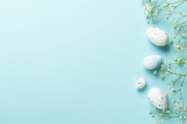 Yumurta ve çiçekli Paskalya arkaplanı. Mavi arka planda düz uzandı.