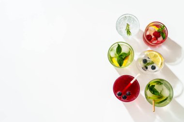 Beyaz arka planda buzlu içecekler. Limonata, mojito, ahududu limonatası, taze meyveli tonik suyu. Metin için boşluk olan üst görünüm.