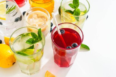 Yaz içkileri, beyaz arka planda renkli kokteyller. Limonata, mojito, ahududu limonatası, tonik ve buzlu kahve..