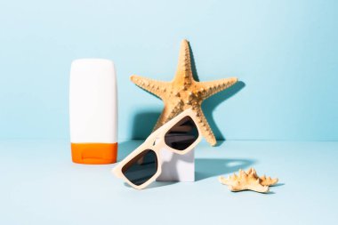 Yaz tatili konsepti. Güneş gözlüğü, güneş kremi ve güneşli gölgeli deniz kabuğu.