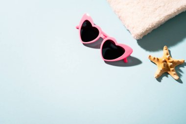 Yaz düzlüğü arka plandaydı. Güneş gözlüğü, beyaz havlu ve güneşli gölgeli deniz kabuğu..