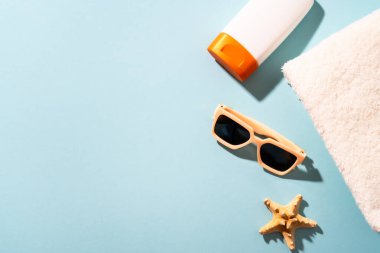 Yaz tatili konsepti. Güneş gözlüğü, güneş kremi ve güneşli gölgeli deniz kabuğu.