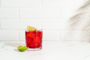 Sert alkol kokteyli. Beyaz arka planda viski, nar şurubu, acı, kireç ve buz olan New Yorklu..
