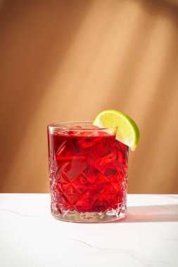 Viski, nar şurubu, acı, limon ve buzlu New Yorker kokteyli. Sert gölgeler, renkli arkaplan