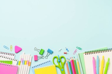 Mavi arka planda okul malzemeleri. Not defterleri, kalemler, kalemler, klipler ve diğerleri. Kopyalama alanı olan düz.