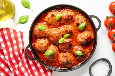 Domates soslu köfte ve beyaz arka planda fesleğen. Düz görünüm.