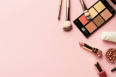Makyaj ürünleri pembeye yatar. Göz farı, fosforlu kalem, krem, ruj ve kozmetik fırçalar..