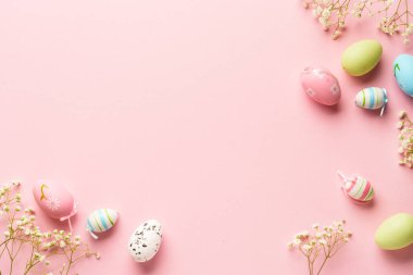 Paskalya arkaplanı pembeye uzanıyordu. Kopya alanı olan renkli yumurta ve çiçekler.