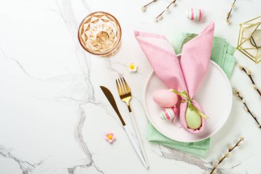 Beyaz arka planda Paskalya sofrası. Beyaz tabak, şarap bardağı, çatal bıçak takımı ve renkli yumurta. Kopyalama alanı olan düz.