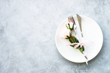 Beyaz tabak ve gül çiçekli bahar masası. Yıldönümü ya da düğün için masa dekorasyonu.