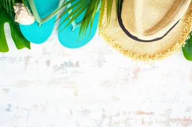 Yaz tatili ve seyahat konsepti. Palmiye yaprakları, şapka, parmak arası terlik ve beyaz arka planda kabuklar. Kopyalama alanı olan düz.