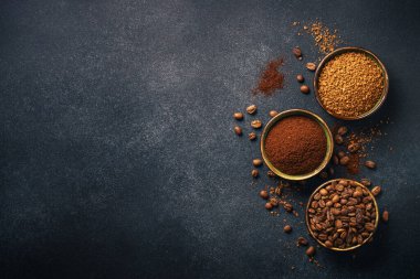 Roasted coffee beans, ground coffee and instant coffee in bowls at dark background. Flat lay image.