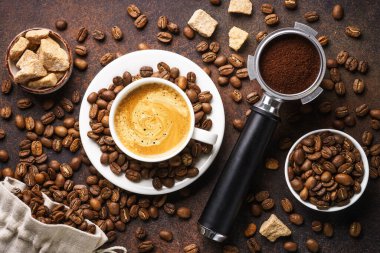 Bir fincan kahve, kavrulmuş kahve çekirdekleri ve koyu masada filtre tutacağı. Üst görünüm