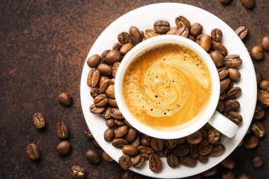 Bir fincan kahve, kavrulmuş kahve çekirdekleri ve koyu masada filtre tutacağı. Kopyalama alanı olan üst görünüm.