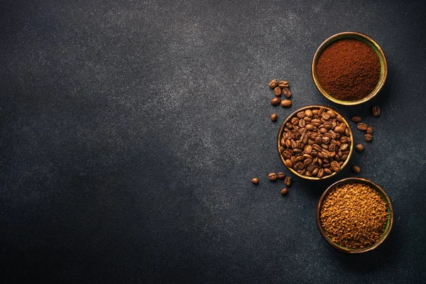 Roasted coffee beans, ground coffee and instant coffee in bowls at dark background. Top view image.