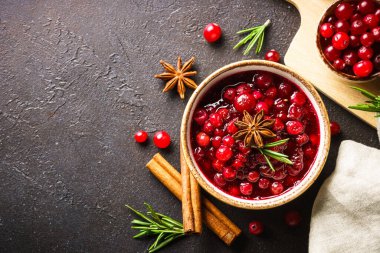 Biberiye ve baharatlı bir kasede kızılcık sosu. Siyah arkaplanda üst görünüm.