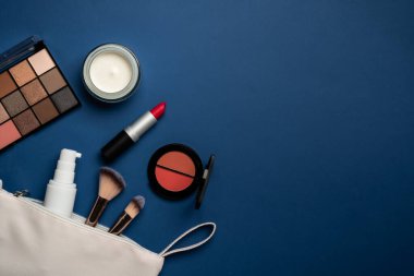 Makyaj düzleştirici, kozmetik ürünler. Yüz kremi, makyaj gölgeleri, ruj, mavi arka planda kozmetik fırçalar.