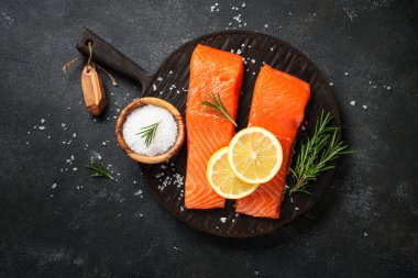 Siyah masada çiğ balık. Limon ve baharatlı somon filetosu. Düz yatıyordu.