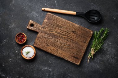 Siyah arka planda çatal bıçak ve otlarla kesme tahtası. Kopyalama alanı olan üst görünüm.