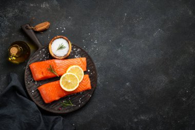 Siyah masada çiğ balık. Limon ve baharatlı somon filetosu. Dizayn için alanı olan düz uzandı.