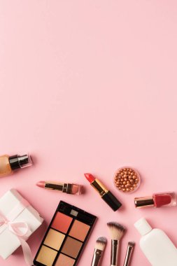 Ürünleri ve hediye kutusunu pembe arka planda hazırla. Göz farı, ruj ve kozmetik fırçalar..