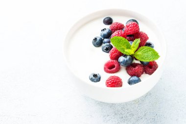 Beyaz kasede taze böğürtlenli yoğurt. Sağlıklı atıştırmalıklar ya da kahvaltı. Diyet yemek..