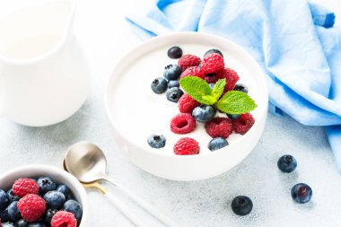 Beyaz kasede taze böğürtlenli yoğurt. Sağlıklı atıştırmalıklar ya da kahvaltı. Diyet yemek..
