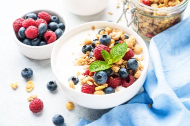 Beyaz masada taze böğürtlenli yoğurt ve tahıl gevreği. Sağlıklı atıştırmalıklar ya da kahvaltı. Diyet yemek..