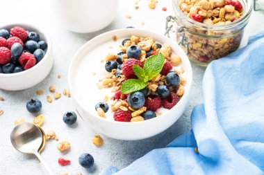 Beyaz masada taze böğürtlenli yoğurt ve tahıl gevreği. Sağlıklı atıştırmalıklar ya da kahvaltı. Diyet yemek..