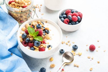 Beyaz masada taze böğürtlenli yoğurt ve tahıl gevreği. Sağlıklı atıştırmalıklar ya da kahvaltı. Diyet yemek..