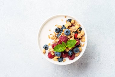 Beyaz masada taze böğürtlenli yoğurt ve tahıl gevreği. Sağlıklı kahvaltı. Üst görünüm.